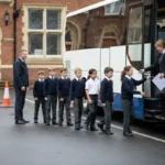 Teachers supervise pupils boarding an unbranded coach for a safe UK school trip